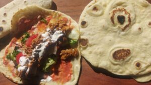 Homemade naan bread with chicken kebab, salad and garlic sauce