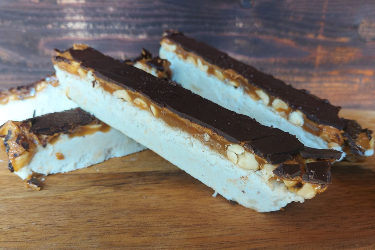 Homemade frozen Snickers bars with cashew, peanut caramel and dark chocolate layers