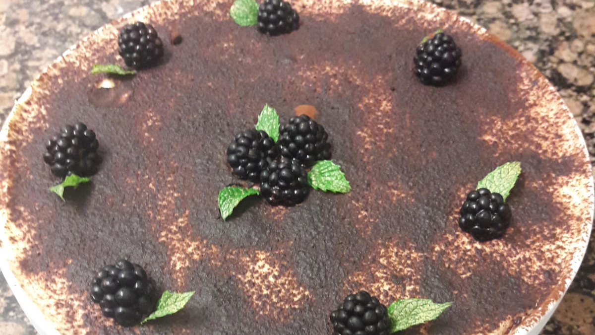 Homemade tiramisu without cream topped with cocoa, blackberries and fresh mint