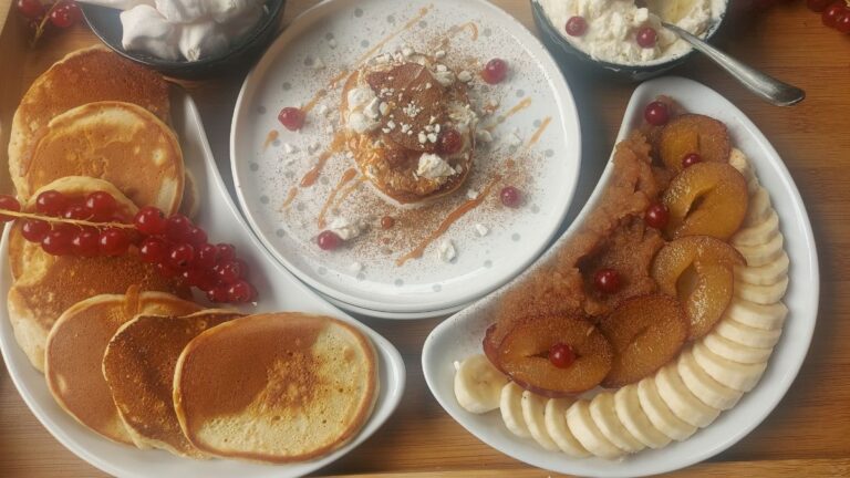 Fluffy American pancakes served with fruit, cream and meringue