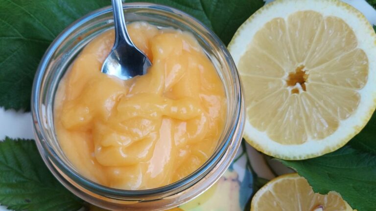 Homemade lemon curd in a glass jar with fresh lemons