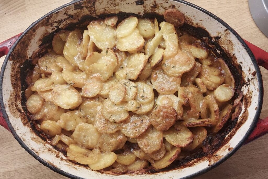 Homemade beef hot pot with golden sliced potatoes and fresh thyme